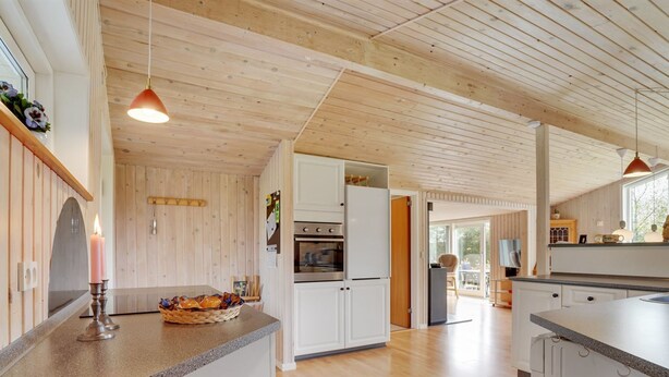 Een moderne keuken met houten balken, een centraal eiland en uitzicht op de eetruimte.