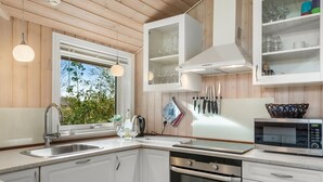 Eine moderne Küche mit weißen Schränken, einer Edelstahl-Spüle, einer Mikrowelle und einem Backofen.