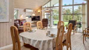 Ein moderner Essbereich mit einem runden Tisch, Holzstühlen und einem Fernseher im Hintergrund.