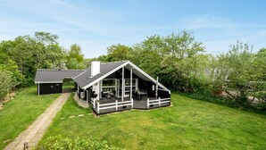 Une maison moderne dotée d’une grande terrasse, d’un garage indépendant et d’une pelouse bien entretenue.