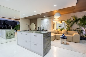 Relax in this stylish living area with a central island, beige sofa, and potted plants.