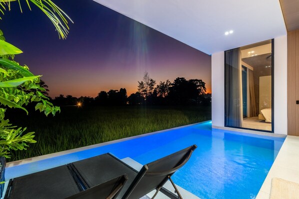 Relax by the pool with a serene view of the surrounding field.