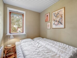 A bedroom with a bed, a window, and wall art.