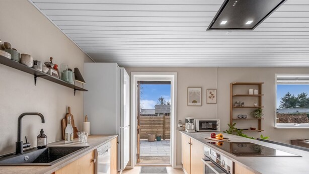 Une cuisine moderne avec des meubles en bois, un four encastré et une grande fenêtre donnant sur un jardin.