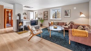 Un salon moderne avec une cheminée, un canapé, une table basse et un téléviseur.