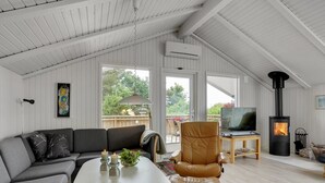 Un salon moderne avec un canapé, un fauteuil en cuir, un téléviseur et un poêle à bois.