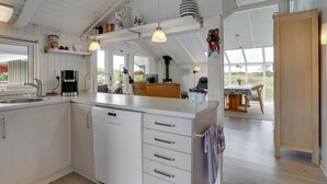 Une cuisine spacieuse avec des meubles blancs, un lave-vaisselle intégré et un coin repas comprenant une table et des chaises.