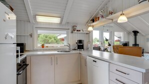 Une cuisine moderne avec des meubles blancs, un lave-vaisselle, une machine à café et une cuisinière.