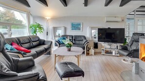 Een moderne woonkamer met leren banken, een ronde salontafel, een flatscreen-tv en een open haard.