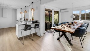 Una cocina moderna con una isla central, taburetes de bar e iluminación colgante.