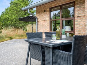 An outdoor patio with a table and chairs, a bottle of olive oil, and a glass of water on a table. - "Thormar" - 1.5km from the sea by Interhome (Blåvand)