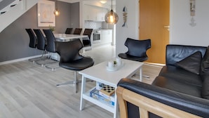 A modern living room with a black leather sofa, a white coffee table, and a dining area with black chairs. A staircase is visible in the background. - "Raine" - 2.3km from the sea by Interhome (Rømø)