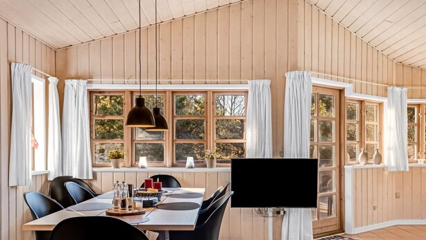 Een eetgedeelte met een houten tafel, zwarte stoelen en een televisie.