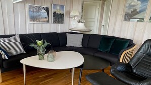 Un salon moderne avec un canapé d’angle noir, une table basse ronde et un fauteuil en cuir noir.
