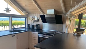 Une cuisine moderne avec une grande fenêtre, un plafond en bois et une vue sur la mer.