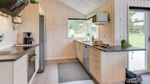 Una cucina moderna con rivestimenti in legno, elettrodomestici in acciaio inossidabile e un'ampia finestra che offre luce naturale.