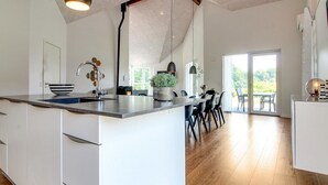 A modern kitchen with a large island, white cabinetry, and a wooden floor.