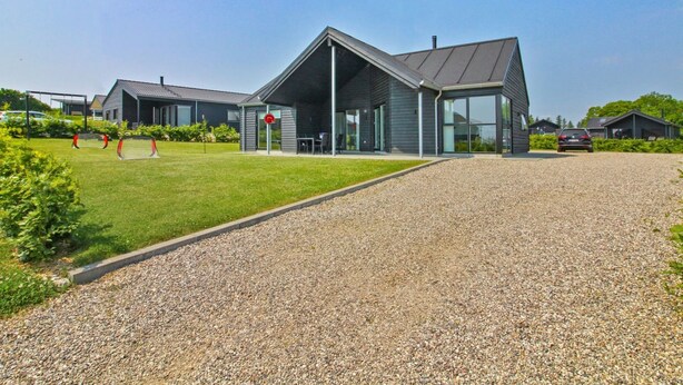 A modern building with a gravel driveway and a grassy area with two soccer goals.