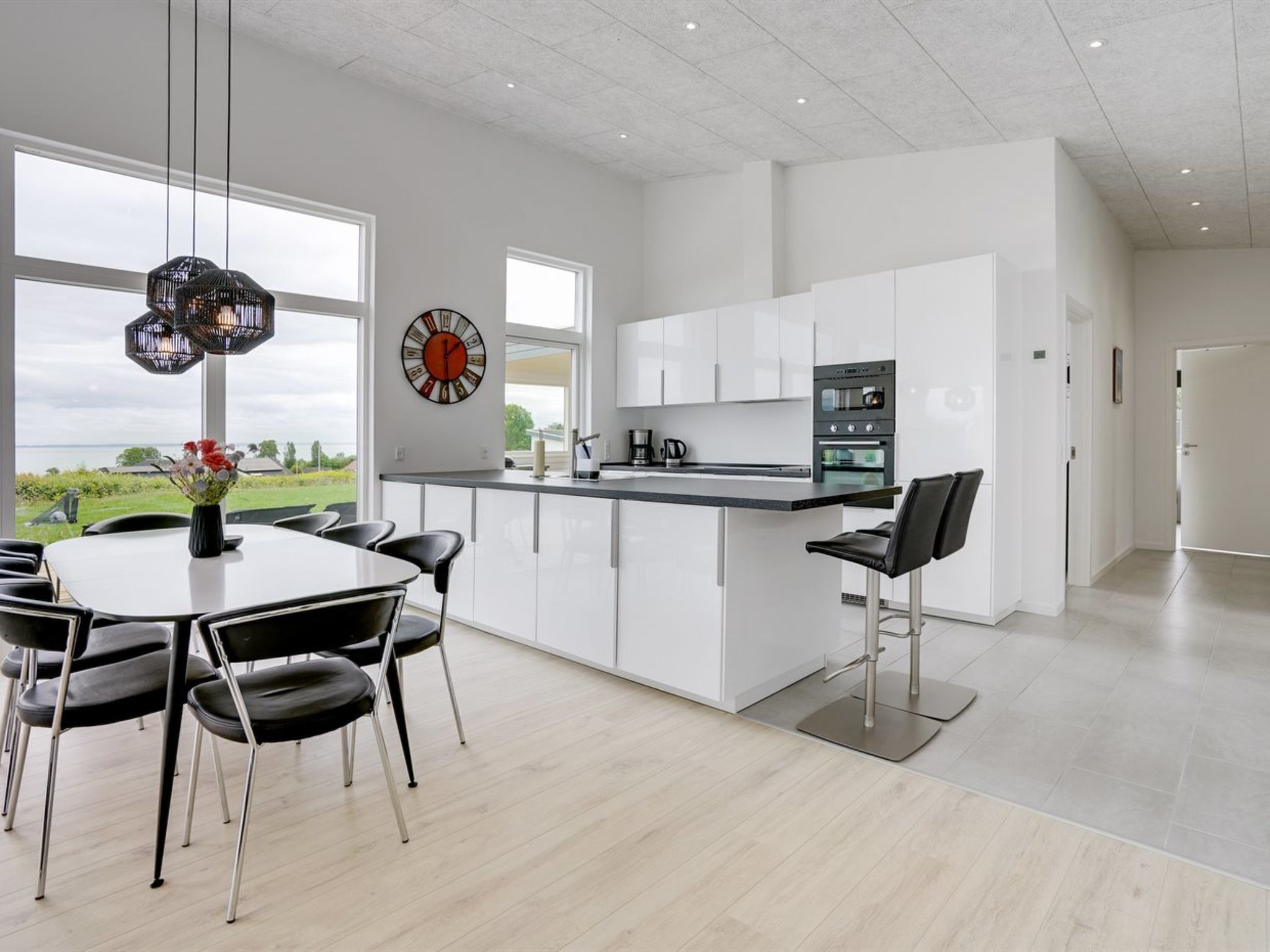 Une cuisine moderne avec des meubles blancs, un îlot central et un coin repas avec des chaises.