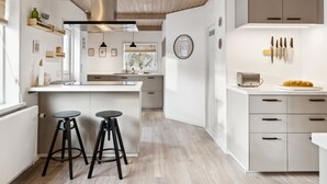 A modern kitchen with white cabinetry, a wooden ceiling, and a central island with stools. - "Dana" - 525m from the sea by Interhome (Tranekær)