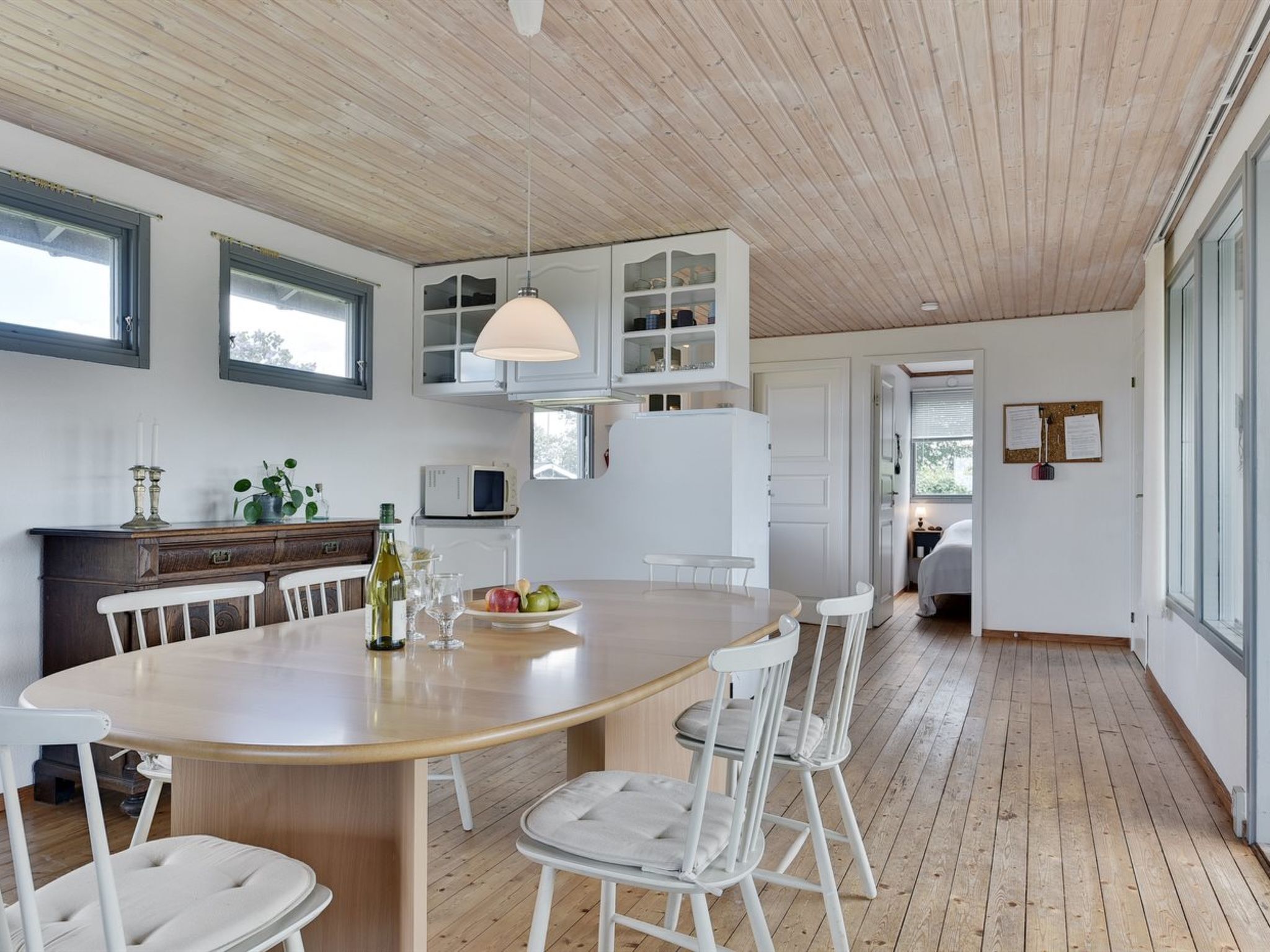 Une cuisine moderne dotée d’un îlot central, de meubles blancs et d’un plafond en bois.