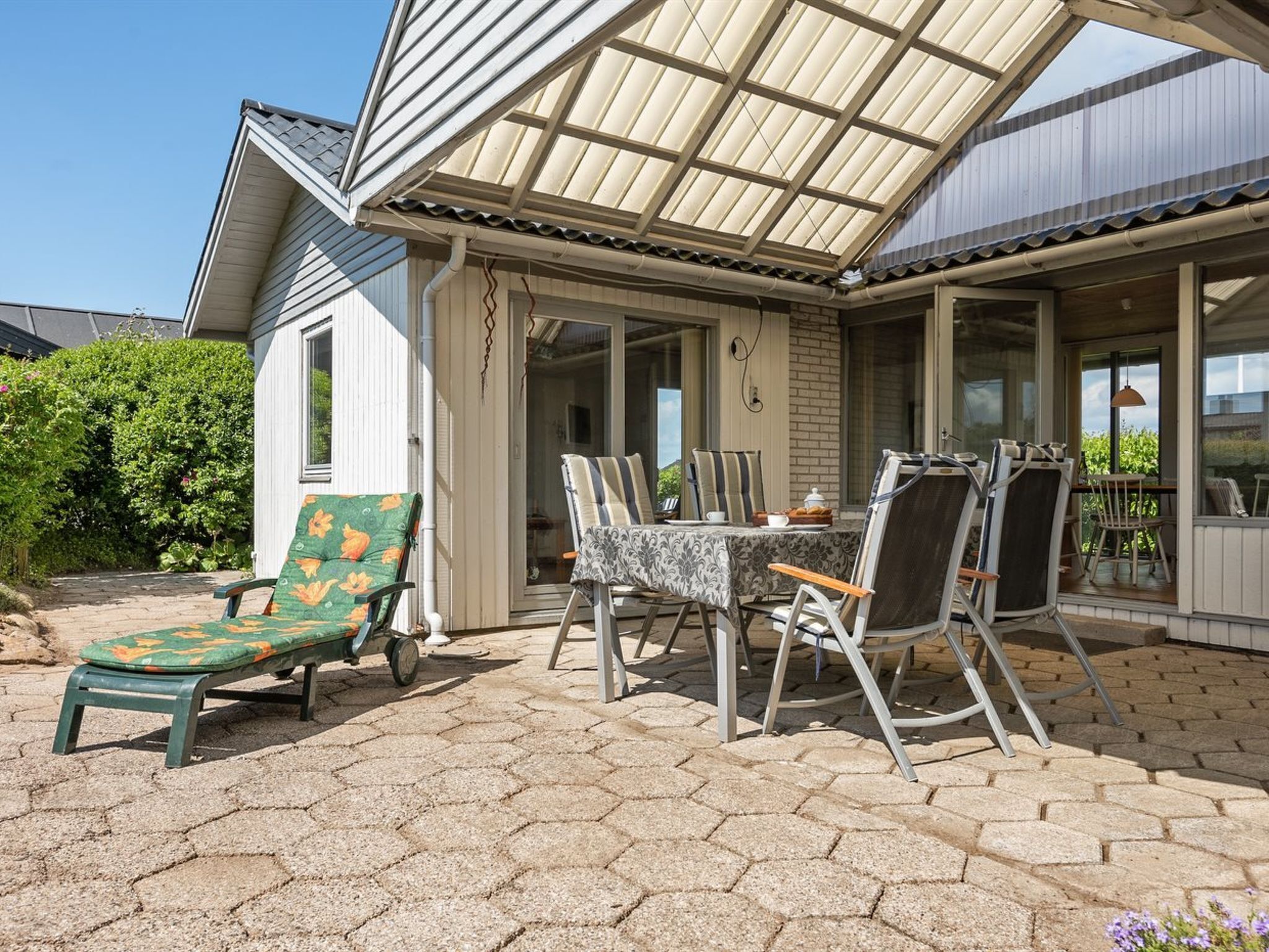 Une terrasse avec une table et des chaises, un fauteuil rembourré et un espace abrité offrant une vue agréable.