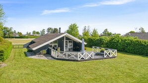 Une maison moderne avec un toit en pente, une terrasse et une cour clôturée.