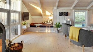 Une pièce chaleureuse et bien éclairée, avec un plancher en bois, un lit offrant une belle vue, un coin salon avec une table et une cheminée.