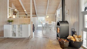 Une cuisine moderne dotée d’un poêle à bois, d’un coin repas et de meubles de cuisine blancs.