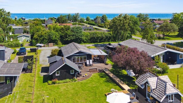 A coastal residential area with houses, a grassy lawn, and a view of the sea.