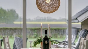 A dining table with a bottle of wine, two candles, a glass, and grapes.