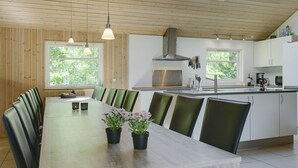 Ett modernt kök med ett stort matbord, gröna stolar och krukväxter.