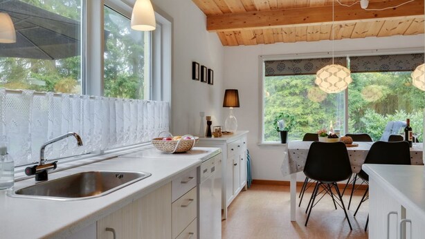 Une cuisine moderne dotée d’une grande fenêtre, d’un plafond en bois et de luminaires suspendus.