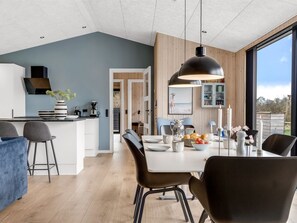 Une cuisine moderne avec un coin repas, des éléments décoratifs en bois et une vue dégagée grâce à de grandes fenêtres.