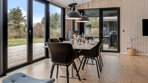Een moderne eetruimte met een grote tafel, zwarte stoelen en hanglampen.
