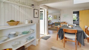 Een lichte, open keuken en eetruimte met houten vloeren, witte kasten en uitzicht op de omgeving.