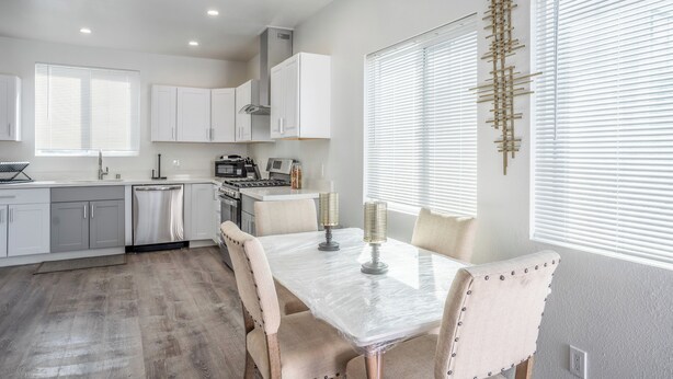 Una cocina moderna con armarios blancos, una mesa de comedor con sillas y un adorno mural.