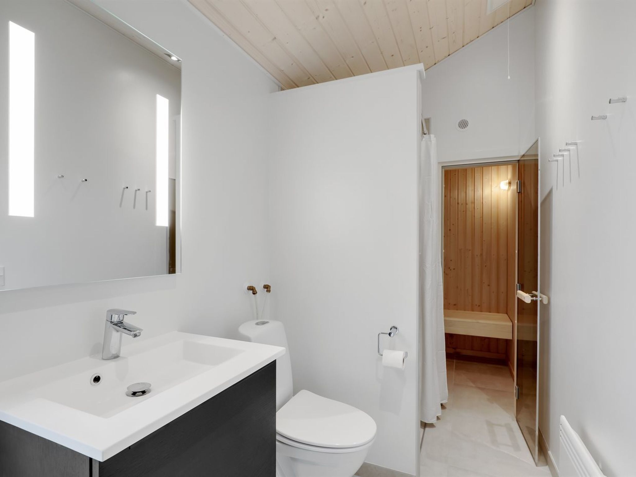 Une salle de bain moderne avec un lavabo blanc, des toilettes et un espace douche.