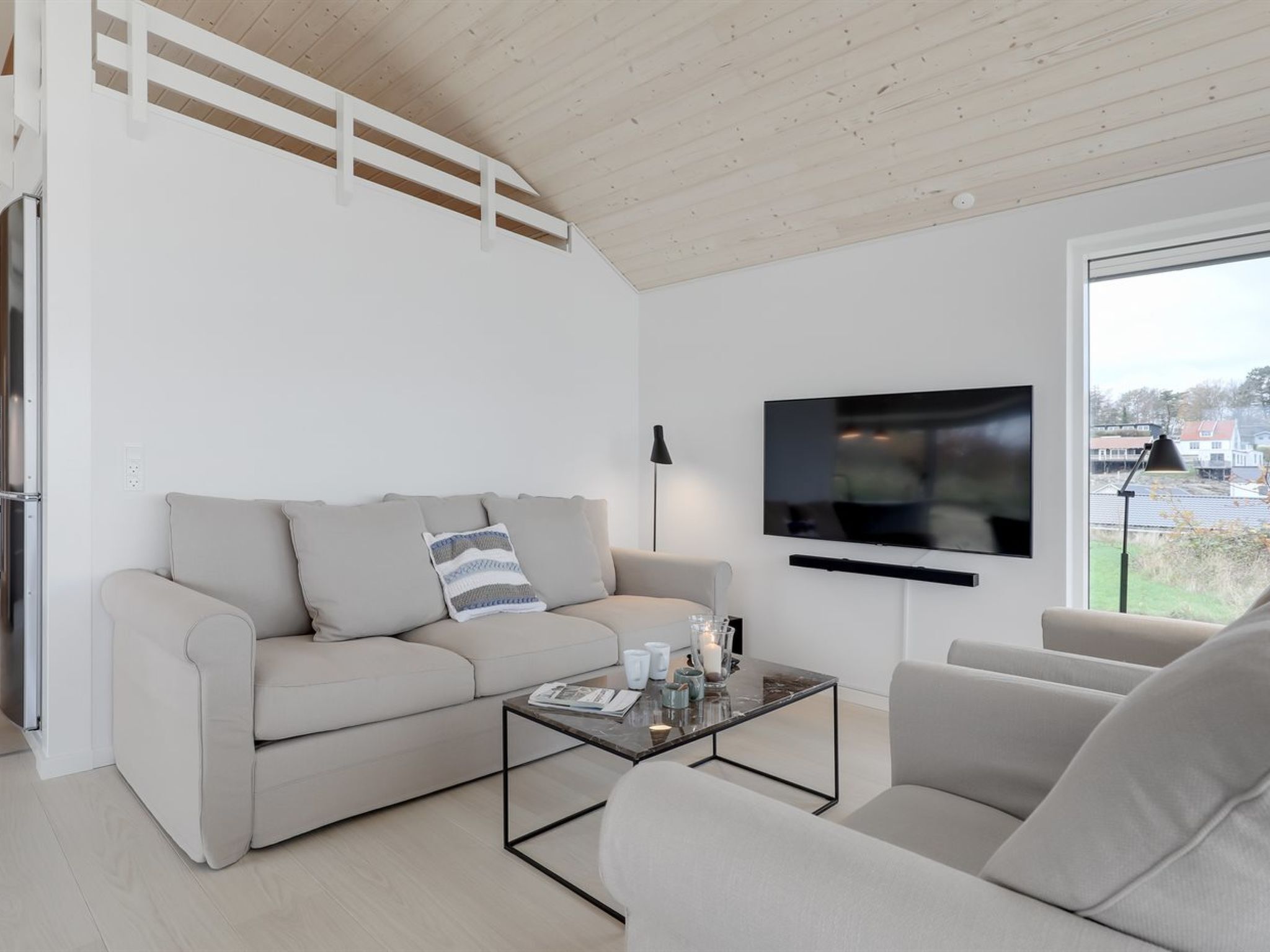 Ein modernes Wohnzimmer mit einer Couch, einem Couchtisch und einem an der Wand befestigten Fernseher.
