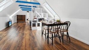 Un loft moderne doté d’un espace repas, de planchers en bois et d’un escalier menant à un niveau supérieur.
