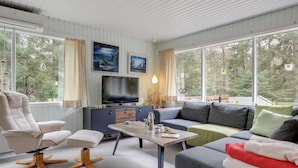 Een moderne woonkamer met een bank, fauteuil en een televisie op een houten kast.