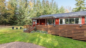 Een chalet met een veranda, grote ramen en een terras.