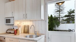 Une cuisine moderne avec des armoires blanches, un évier en acier inoxydable, un four à micro-ondes et un grille-pain.