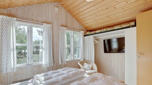 Une chambre avec deux lits, une télévision et une fenêtre avec des rideaux.