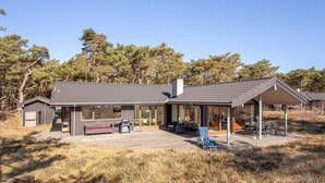 Ett modernt hus med en täckt uteplats, utomhusmöbler och en terrass.