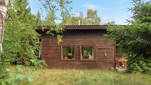 Une cabane en bois avec deux fenêtres, entourée de verdure.