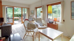 Une pièce confortable avec une table à manger, des chaises, un téléviseur et une fenêtre avec des rideaux.