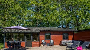 Une terrasse extérieure moderne comprenant un espace repas, des sièges et une partie abritée.