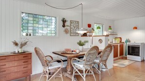 Une cuisine avec une table à manger, des chaises en osier, un buffet en bois et une cuisinière.
