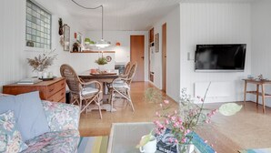 Un salon moderne comprenant un canapé, une table à manger, des chaises et un téléviseur.